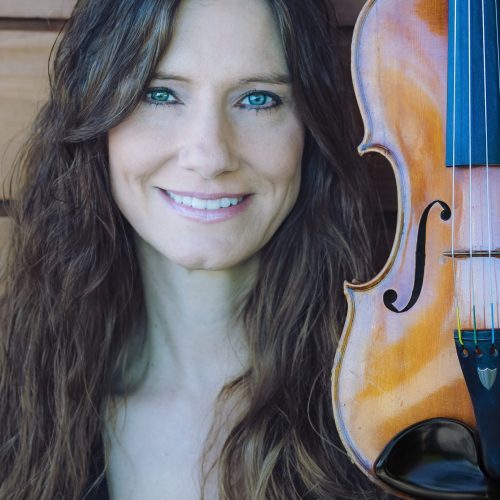 Woman smiling and a violin beside her.